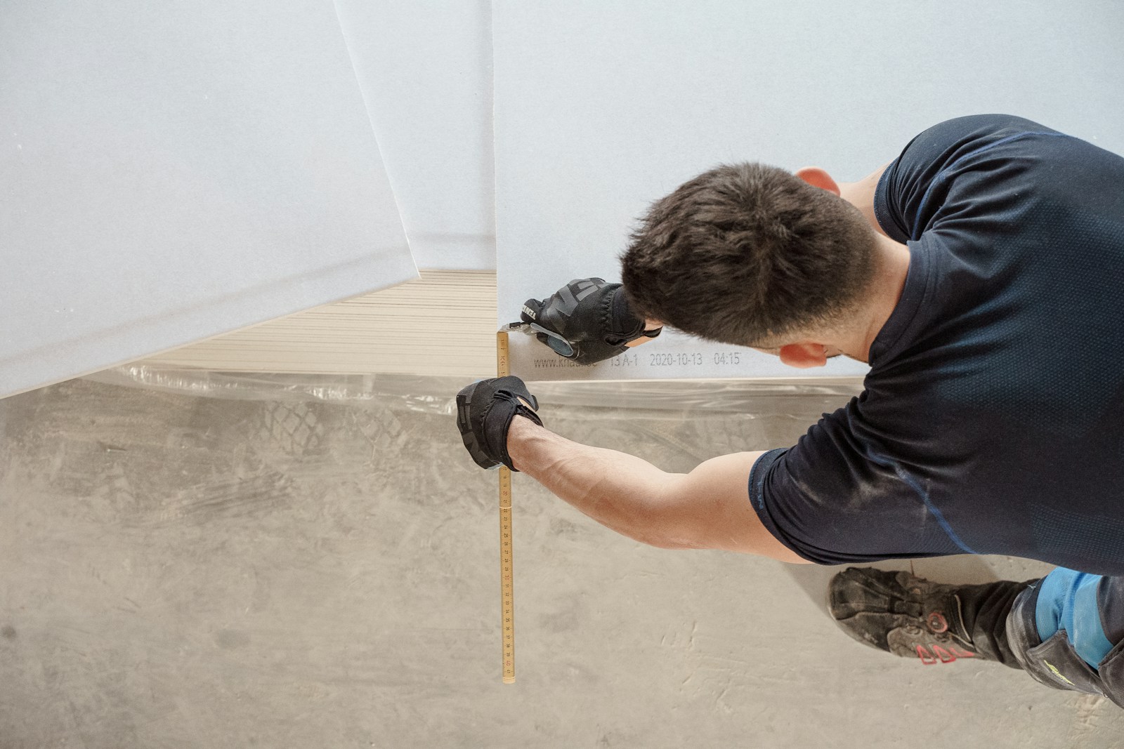 Carpenter wearing work gloves carefully measuring a board during interior renovation