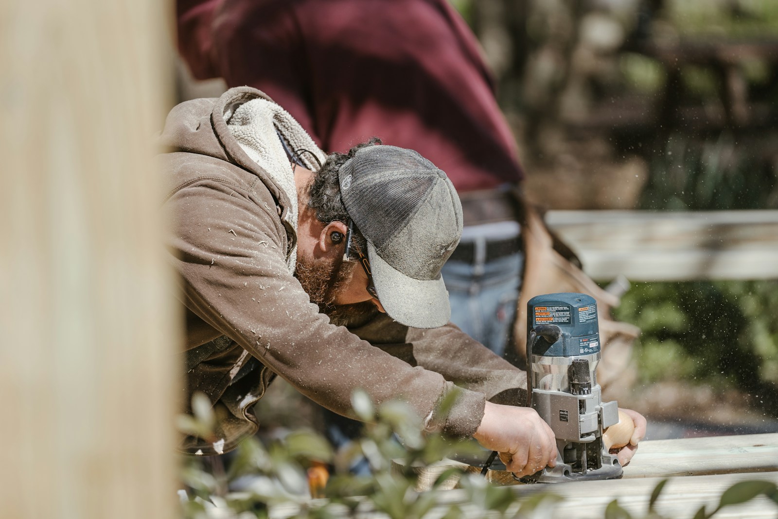 Craftsman using a router to shape timber for an outdoor deck